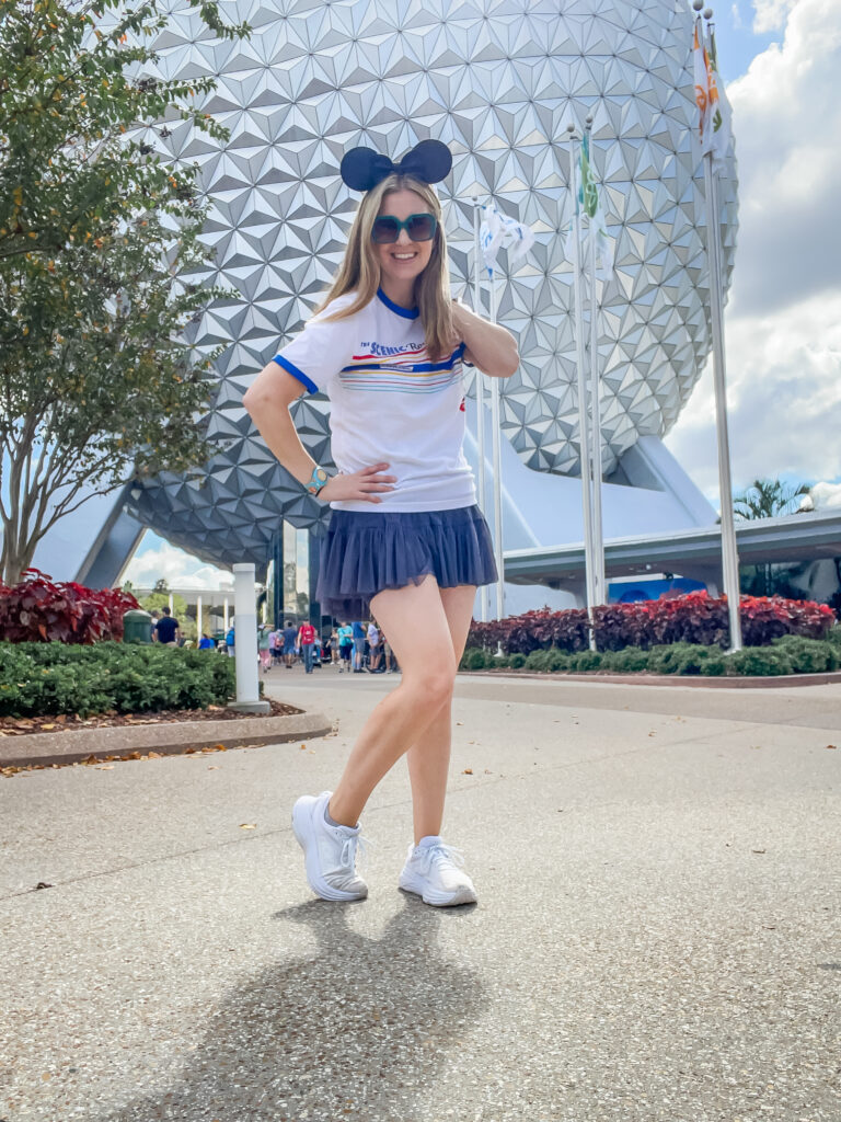 Mom in a Disney Outfit of Popflex Active grey skirt and Disney skyliners t-shirt standing in EPCOT