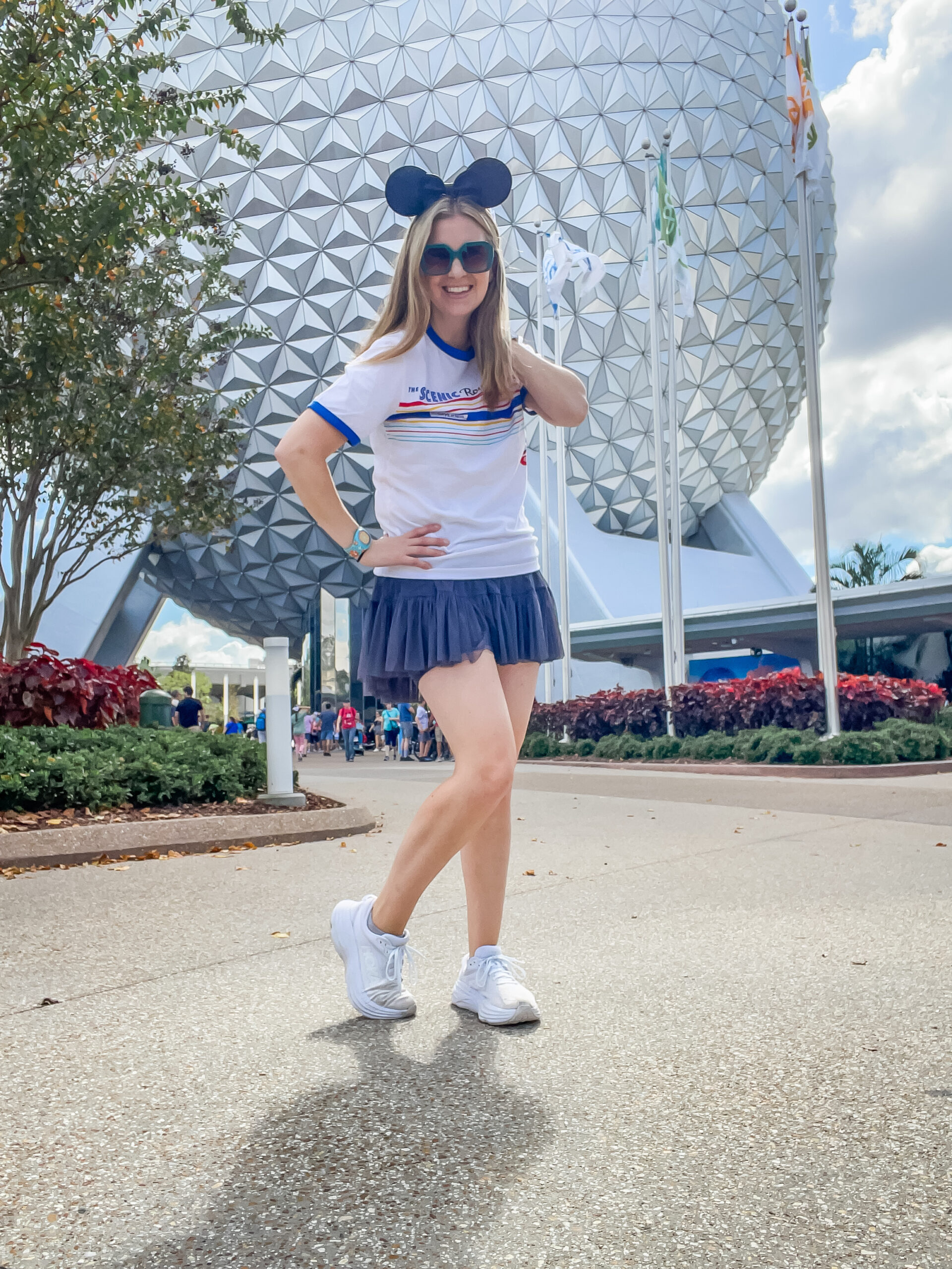 Mom in a Disney Outfit of Popflex Active grey skirt and Disney skyliners t-shirt standing in EPCOT