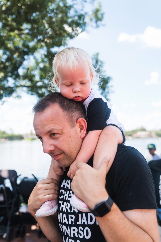 Tired toddler on dads shoulders in Disney World