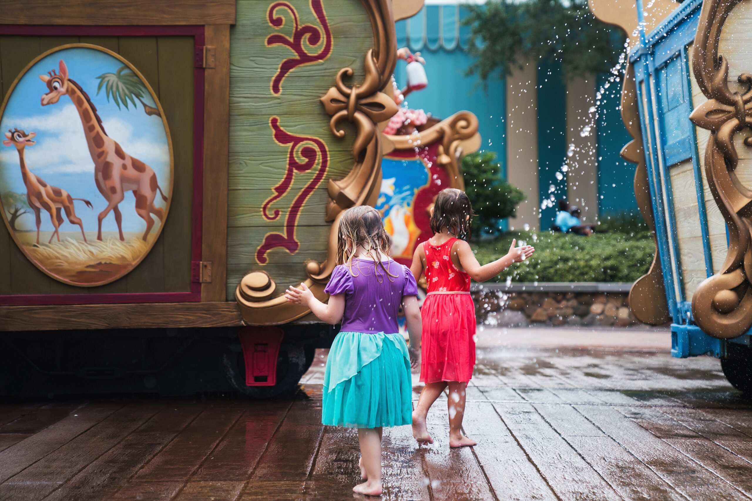 Girls running through water at Caseys Splash pad in Magic Kingdom while waiting for a lightnign lane in summer