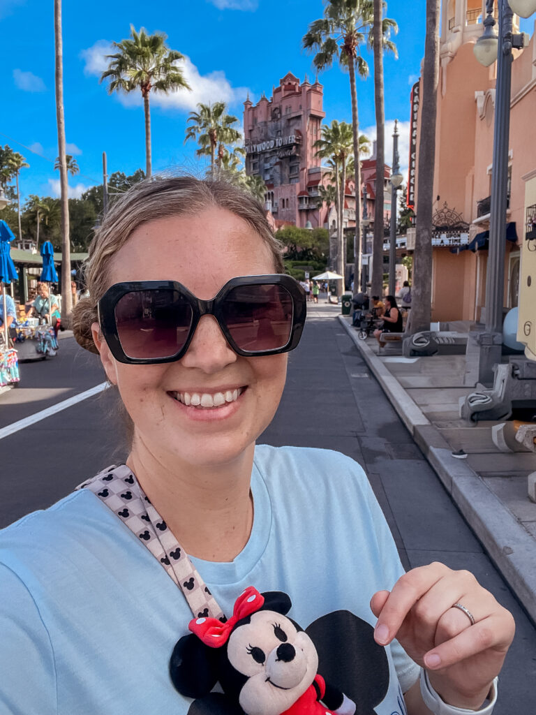 Neyssa Lee with sunglasses on a sunny day using lightning lanes at Hollywood Studios, standing in front of Tower of Terror